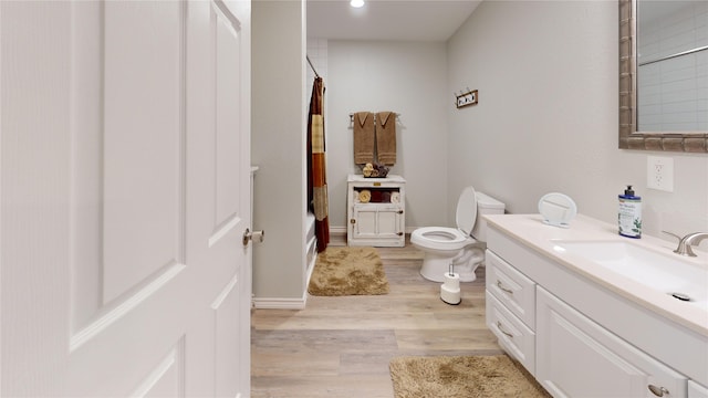 full bathroom featuring toilet, vanity, hardwood / wood-style flooring, and shower / tub combo with curtain