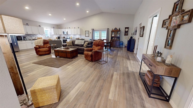 living room featuring light hardwood / wood-style floors and high vaulted ceiling