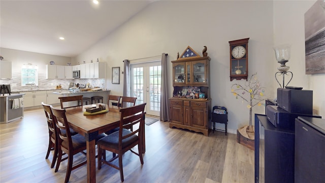 dining space with french doors, high vaulted ceiling, and light wood-type flooring