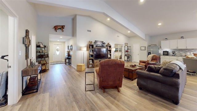 living room featuring high vaulted ceiling and light hardwood / wood-style flooring