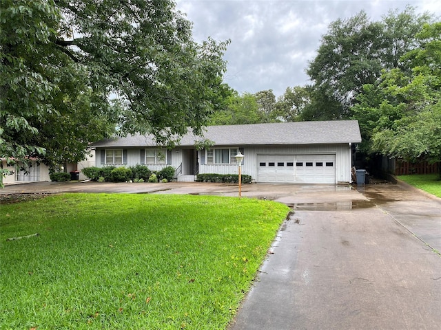 ranch-style home featuring a front yard, a garage, driveway, and roof with shingles