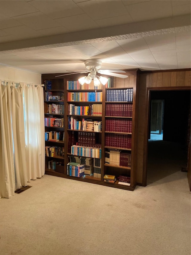 unfurnished room featuring wooden walls, carpet flooring, visible vents, and a ceiling fan