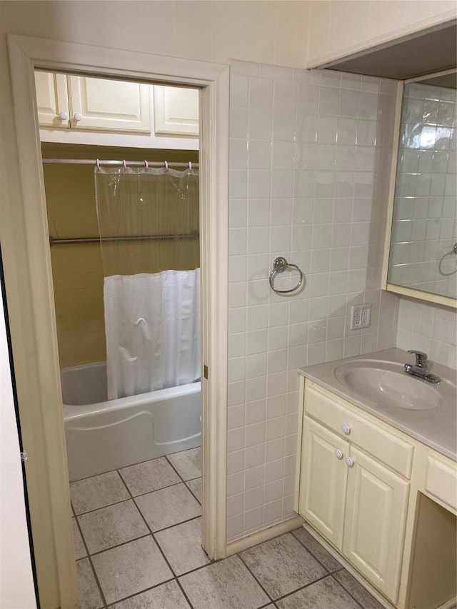 full bath with tile patterned flooring, tile walls, shower / bathtub combination with curtain, and vanity