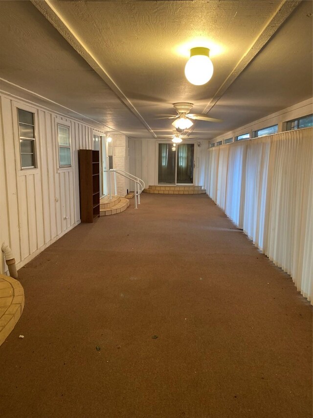 below grade area with ceiling fan, a textured ceiling, and carpet
