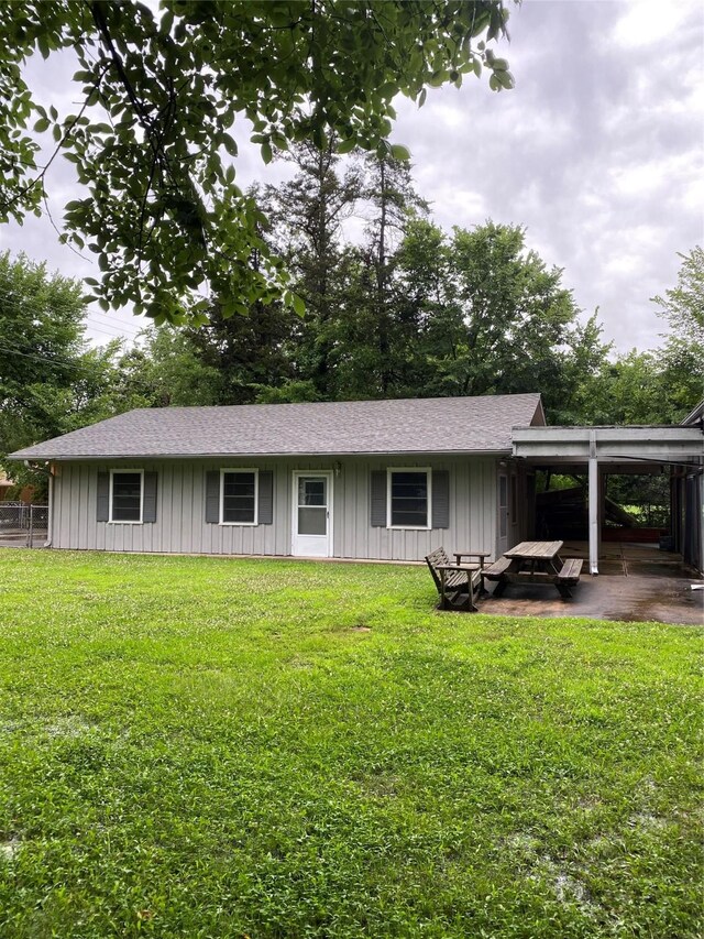 view of front of property with an attached carport, board and batten siding, and a front lawn