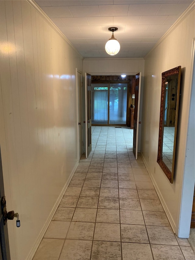 corridor featuring ornamental molding and light tile floors