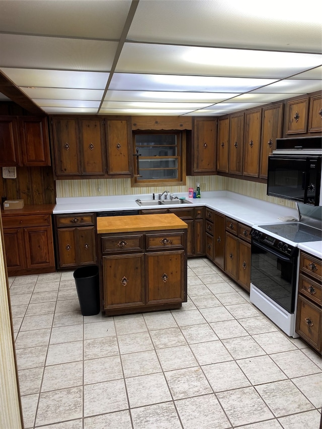 kitchen featuring light tile floors, dark brown cabinetry, sink, and white range with electric stovetop