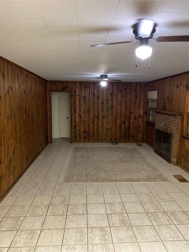 basement with light tile floors, wooden walls, ceiling fan, and a fireplace