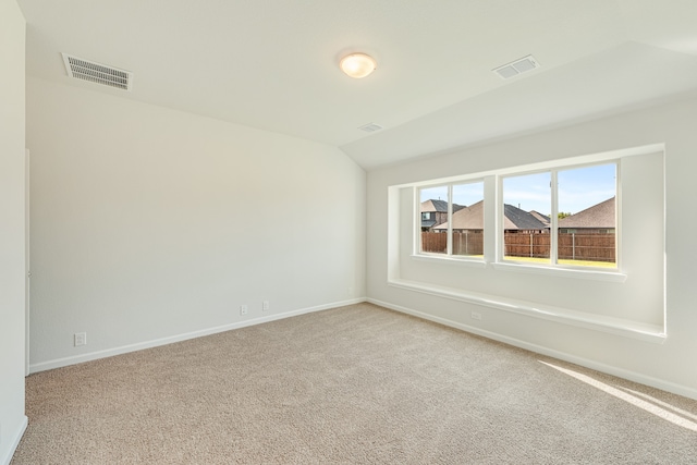 carpeted empty room featuring lofted ceiling