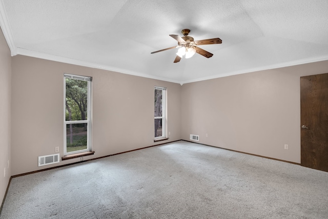 spare room with ceiling fan, a textured ceiling, lofted ceiling, carpet, and ornamental molding