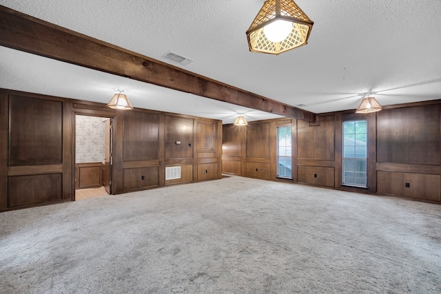 unfurnished living room with light carpet, wooden walls, and a textured ceiling