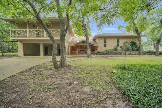 view of front facade featuring a carport, brick siding, a front yard, a balcony, and concrete driveway