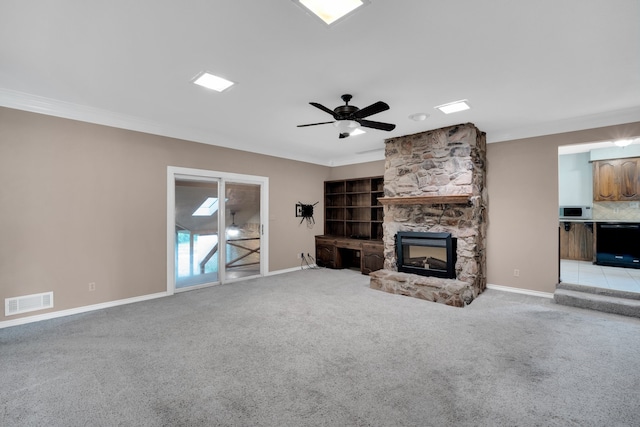 unfurnished living room featuring ceiling fan, light colored carpet, ornamental molding, and a fireplace