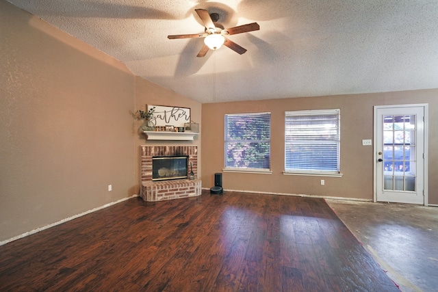 unfurnished living room featuring a brick fireplace, vaulted ceiling, ceiling fan, a textured ceiling, and dark hardwood / wood-style flooring