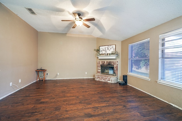 unfurnished living room featuring ceiling fan, dark hardwood / wood-style flooring, lofted ceiling, a textured ceiling, and a fireplace