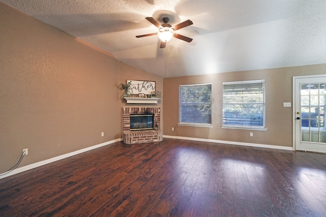 unfurnished living room with ceiling fan, dark wood-type flooring, a brick fireplace, lofted ceiling, and a textured ceiling