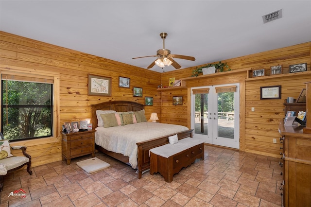 bedroom featuring ceiling fan, french doors, wood walls, and access to outside