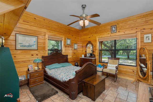 bedroom featuring multiple windows, wooden walls, and ceiling fan