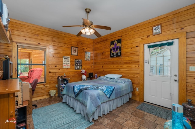 bedroom with ceiling fan and wooden walls