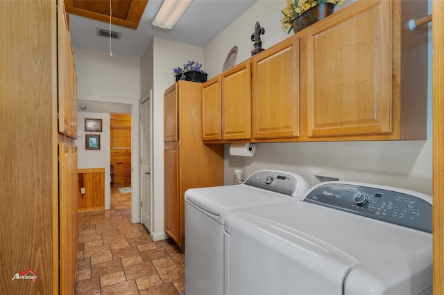 washroom with cabinets, wooden walls, and washing machine and dryer