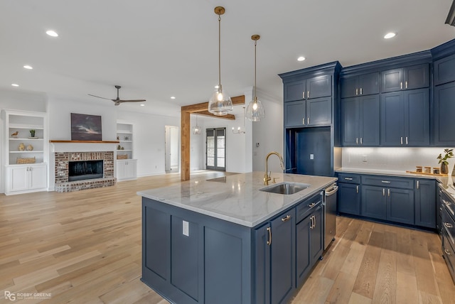 kitchen featuring a fireplace, blue cabinets, sink, and pendant lighting