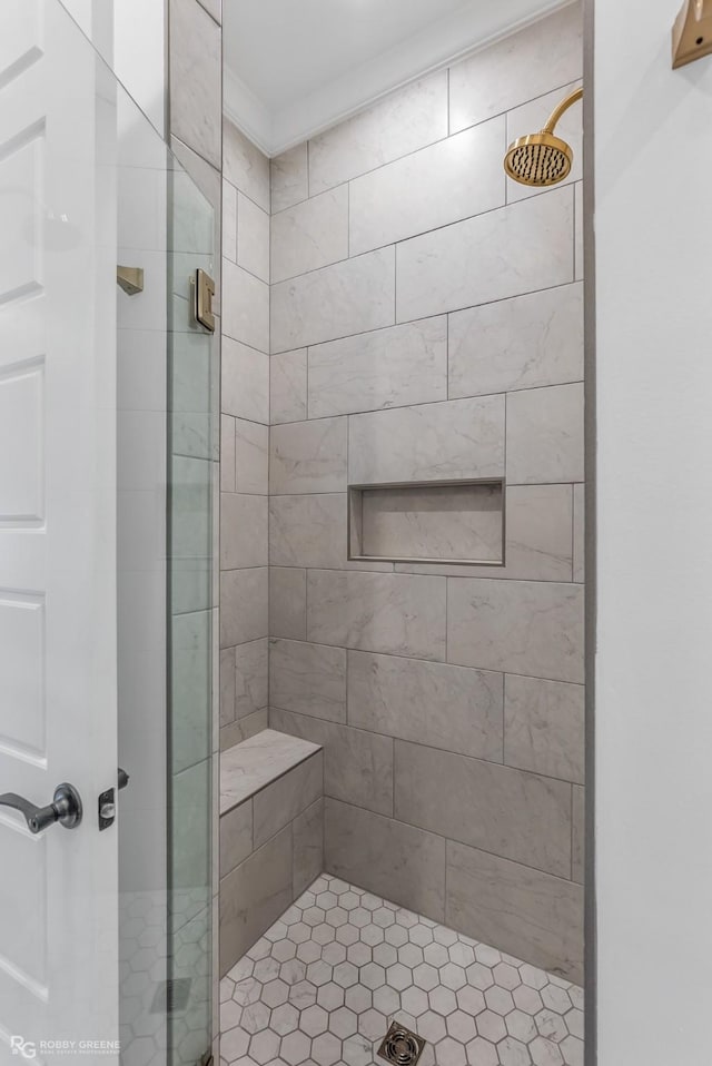 bathroom with a shower with shower door and ornamental molding