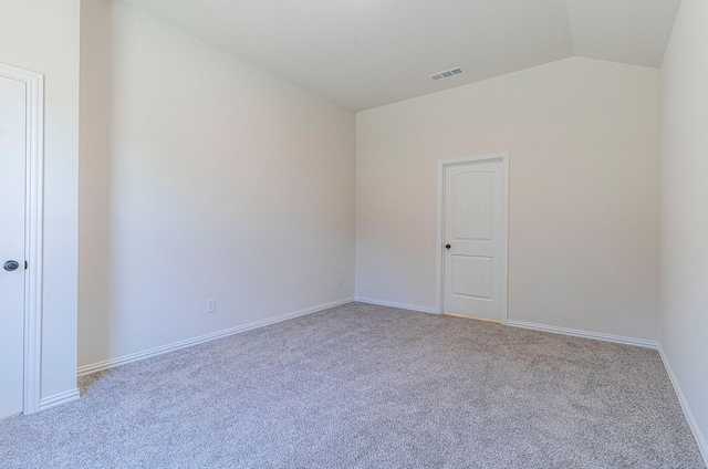 carpeted empty room featuring vaulted ceiling