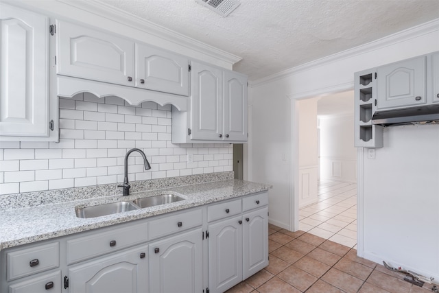 kitchen featuring tasteful backsplash, crown molding, sink, white cabinets, and light tile patterned floors