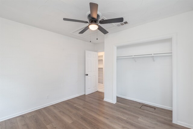 unfurnished bedroom featuring ceiling fan, a closet, and hardwood / wood-style floors