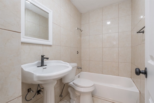 bathroom featuring tile walls, tiled shower / bath combo, toilet, and tile patterned floors