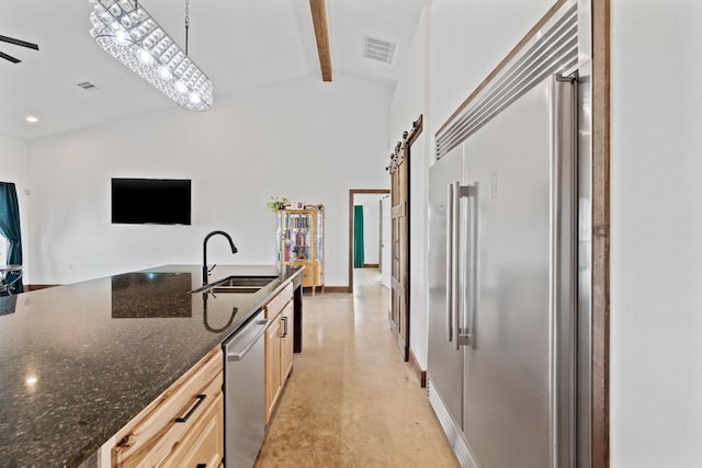 kitchen featuring appliances with stainless steel finishes, decorative light fixtures, sink, a barn door, and beam ceiling