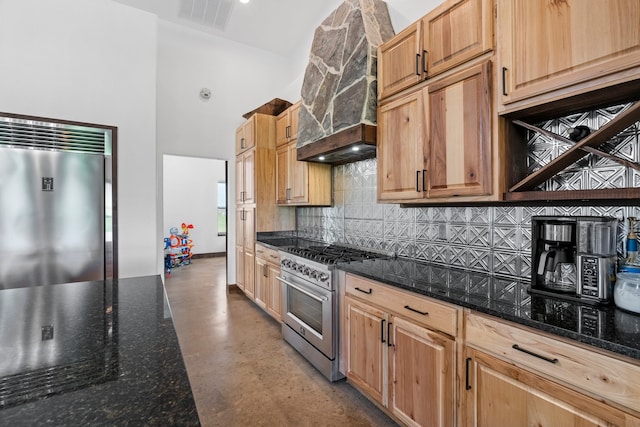 kitchen featuring high end stainless steel range oven, premium range hood, tasteful backsplash, and fridge