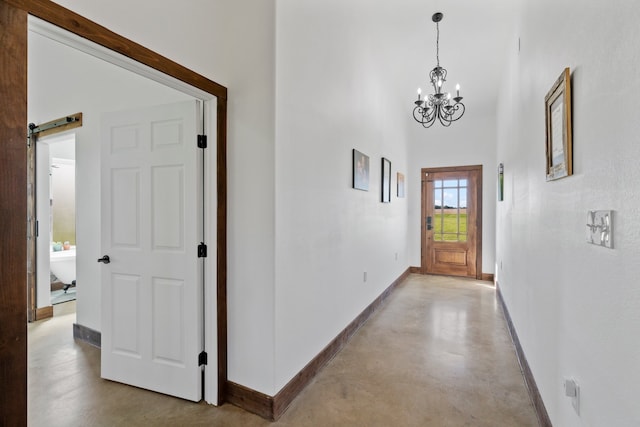 interior space with an inviting chandelier, a high ceiling, concrete floors, and a barn door