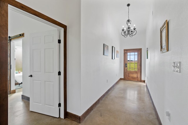 hallway with a high ceiling, a barn door, and an inviting chandelier