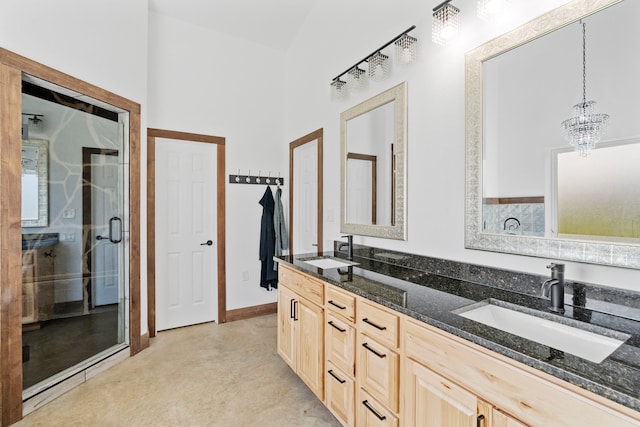 bathroom featuring a notable chandelier, dual vanity, and walk in shower