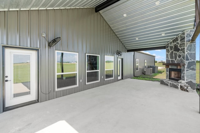 view of terrace with an outdoor stone fireplace and central AC unit