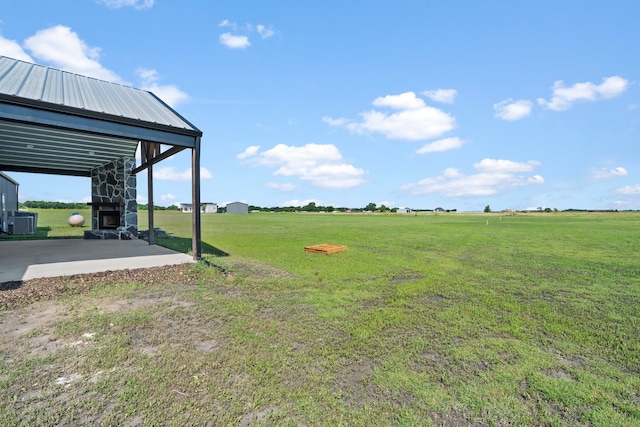 view of yard featuring an outdoor structure, a rural view, and central AC unit