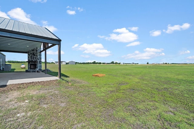 view of yard featuring cooling unit, a fireplace, and a rural view