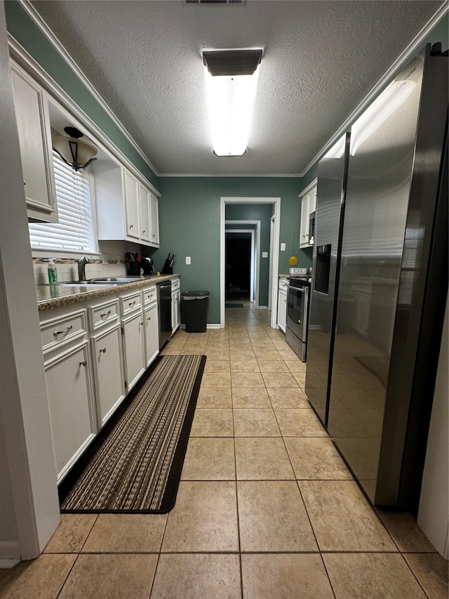 kitchen featuring ornamental molding, a textured ceiling, appliances with stainless steel finishes, light tile patterned flooring, and white cabinetry