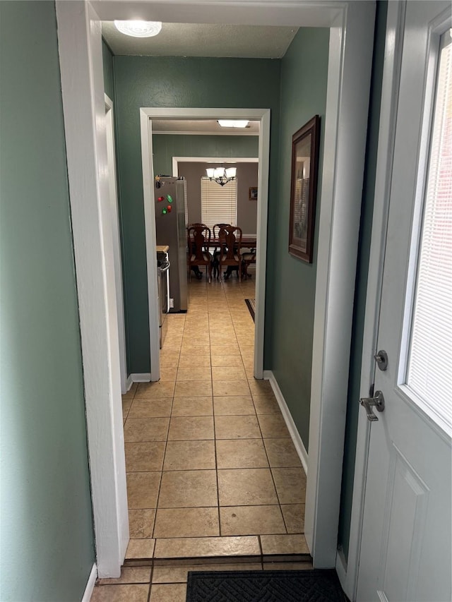 corridor with light tile patterned floors and a notable chandelier