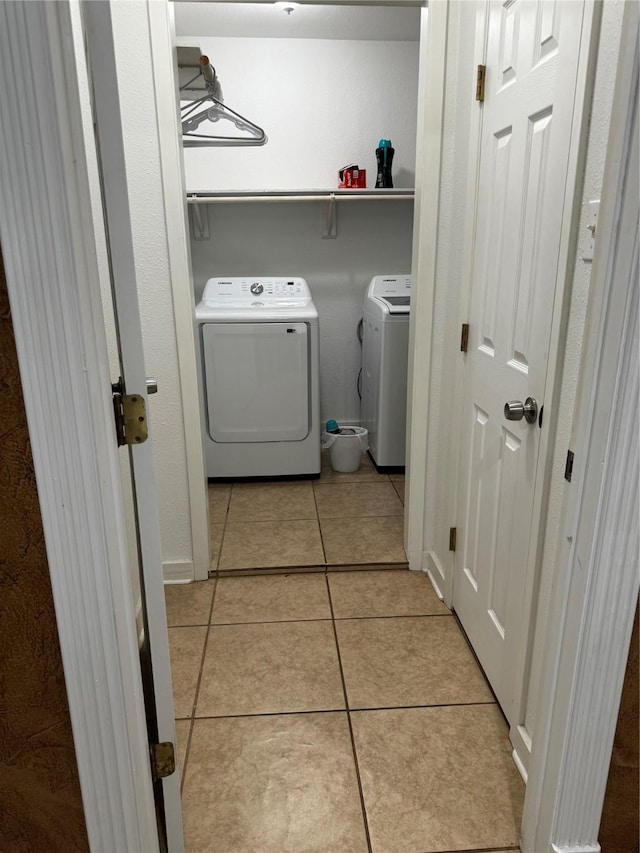 laundry area with independent washer and dryer and light tile patterned floors