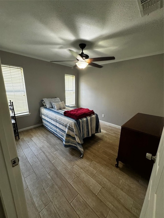 bedroom with a textured ceiling, ceiling fan, multiple windows, and light hardwood / wood-style flooring