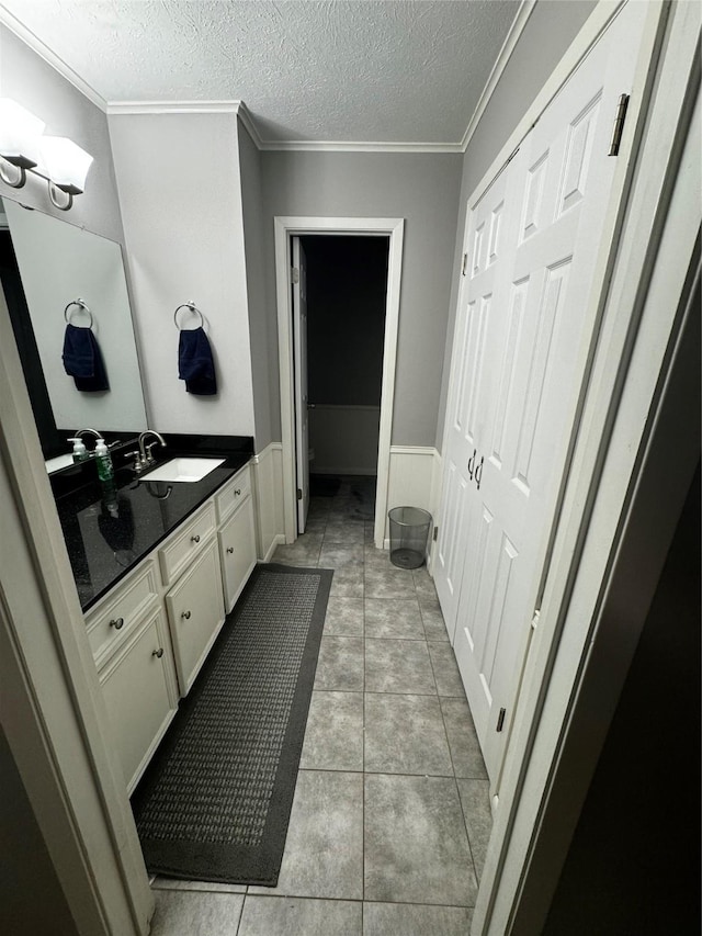 bathroom featuring tile patterned floors, vanity, crown molding, and a textured ceiling