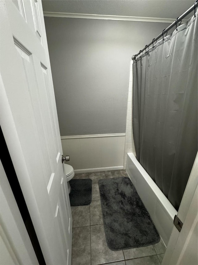 bathroom with shower / tub combo with curtain, tile patterned flooring, ornamental molding, and toilet