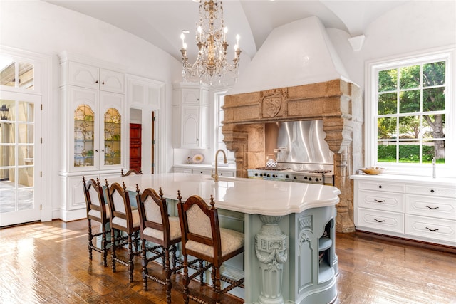 kitchen featuring an island with sink, a healthy amount of sunlight, and white cabinets