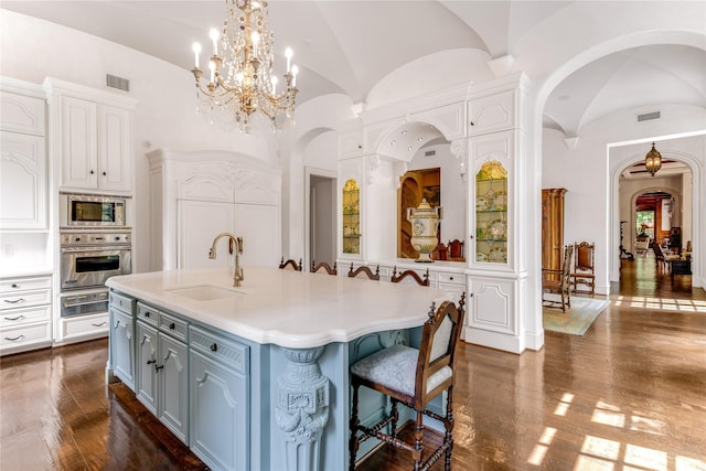 kitchen featuring lofted ceiling, sink, white cabinetry, a center island with sink, and appliances with stainless steel finishes