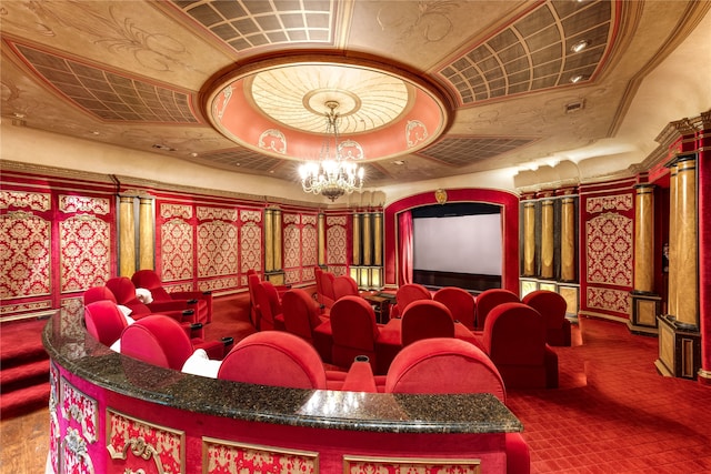 home theater room with a notable chandelier and a tray ceiling