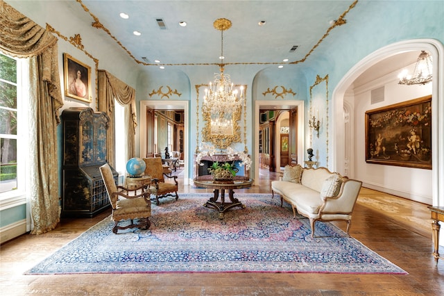 sitting room with wood-type flooring, a notable chandelier, ornamental molding, and plenty of natural light