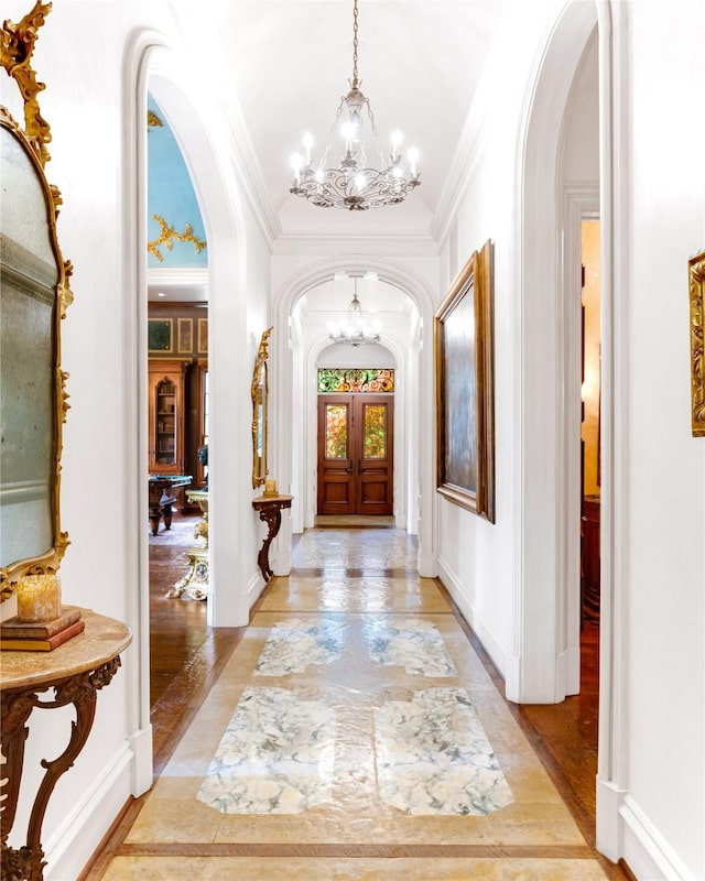 foyer featuring a notable chandelier, crown molding, french doors, and light wood-type flooring