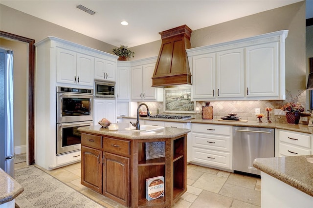 kitchen featuring white cabinetry, stainless steel appliances, sink, and premium range hood